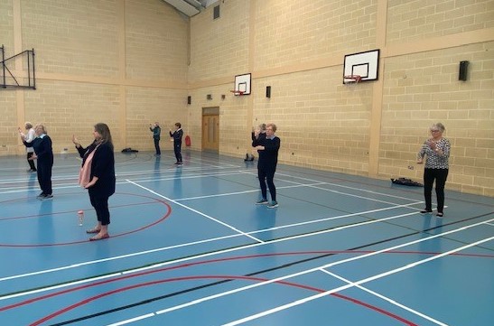 Group of older people taking part in socially distanced Tai Chi