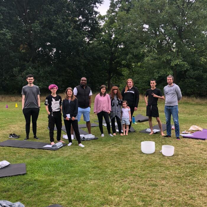 Group of young carers taking part in yoga on a field. 